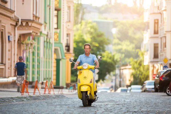 Mature guy riding yellow scooter.