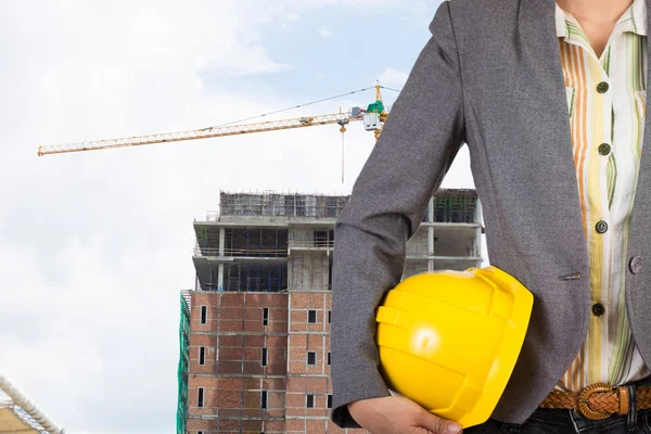 Engineer holding yellow helmet for workers security on backgroun