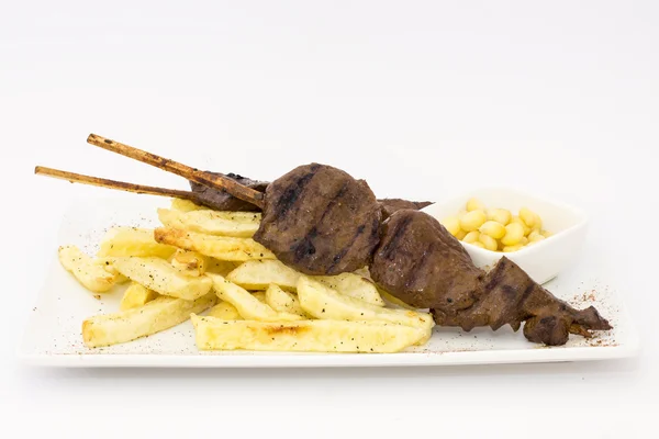 Anticuchos, Peruvian cuisine, grilled skewered beef heart meat with fries potatoes (french fries), white corn and rocoto (chili) sauce