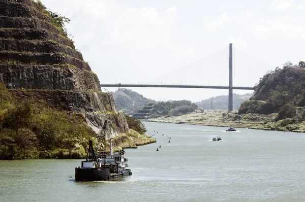 Passing Panama Canal near the bridge with small tug.