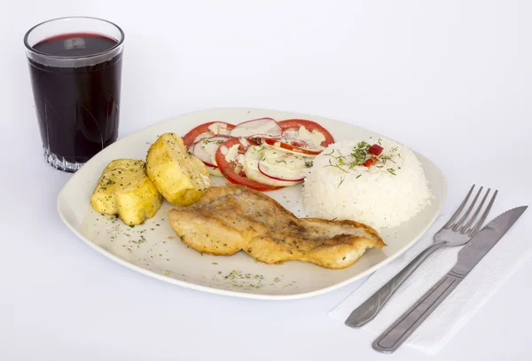 Grilled fish and vegetables, potatoes, rice, tomatoes and a glass of chicha,