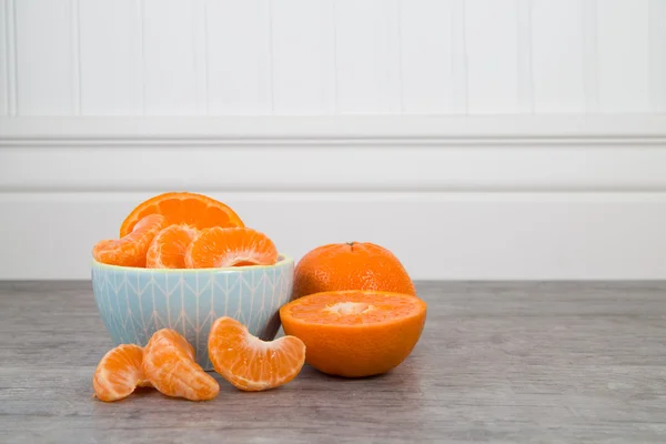 Mandarin orange slices in a blue bowl on a wooden table