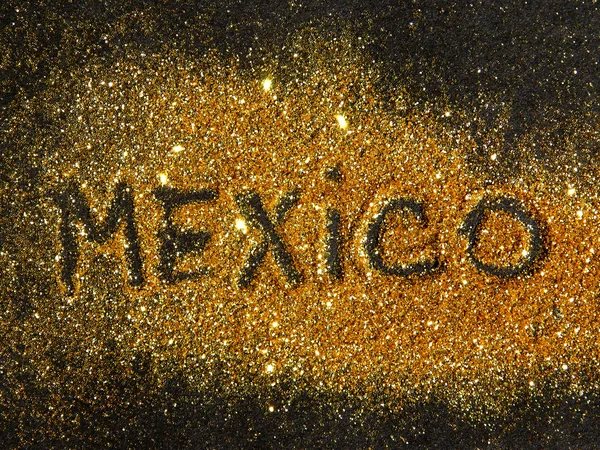 Blurry inscription Mexico on golden glitter sparkle on black background