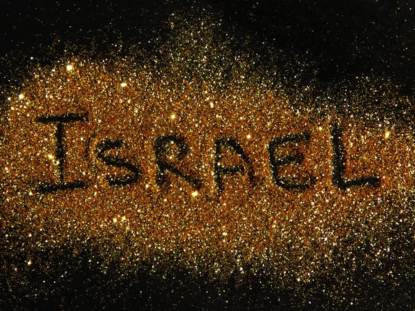 Blurry inscription Israel on golden glitter sparkles on black background