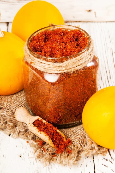 Homemade sugar scrub with a pumpkin on a wooden background