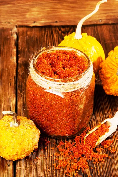 Homemade sugar scrub with a pumpkin on a wooden background