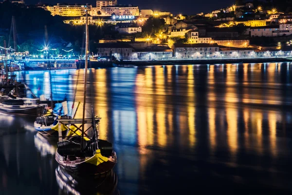 Porto, Portugal. View of the Old Town. Night cityscape. Douro river with the traditional Rabelo boats in the night the light of lanterns.