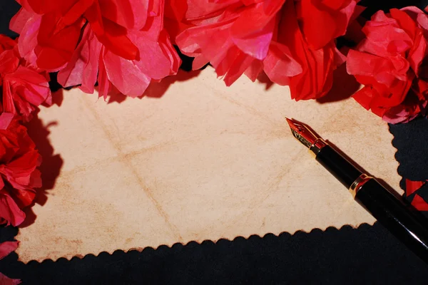 Old paper, quill pen and paper flowers on a wooden surface