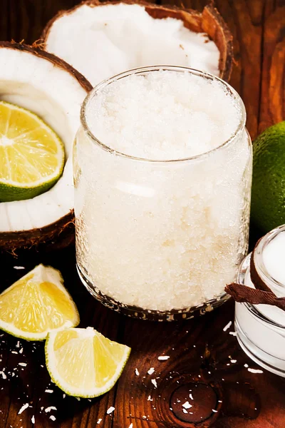 Homemade sugar scrub with lime and coconut on wooden background