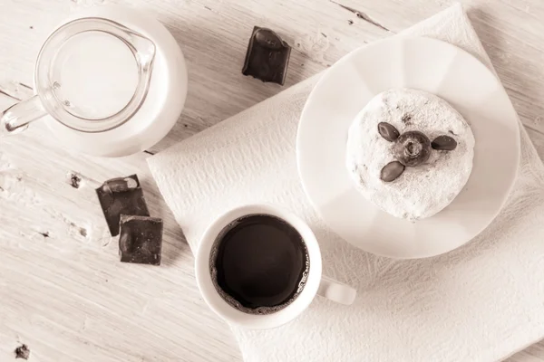 Cup of coffee with jug of milk cake and chocolate on the white table top view