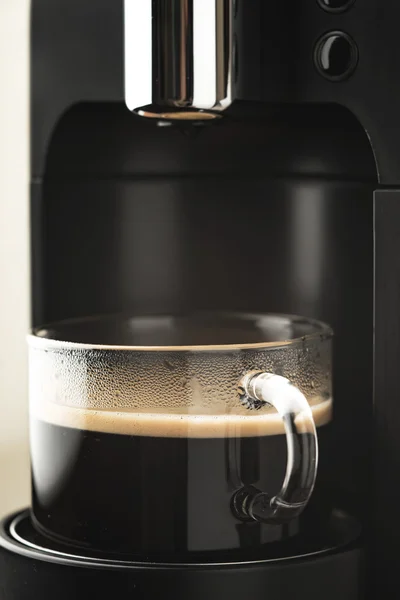 Cup of coffee in the coffee maker vertical