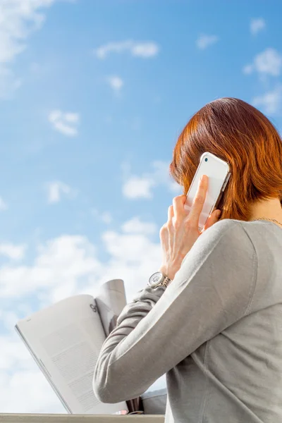 Woman talking on the mobile phone on the blue sky background