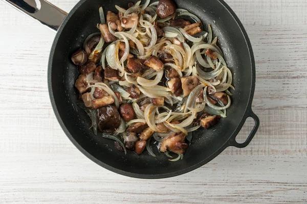 Fried white mushrooms and onions in a cast-iron frying pan