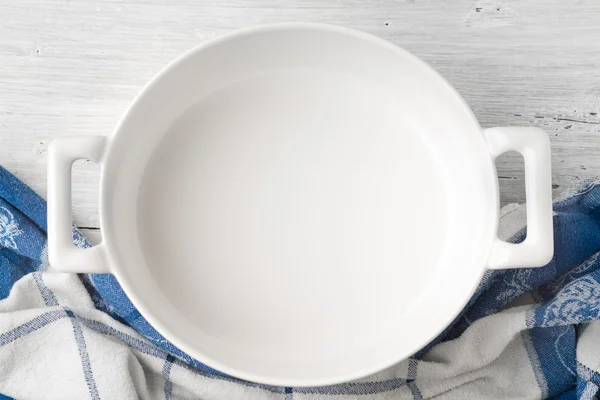 Empty ceramic pan on the white wooden table top view