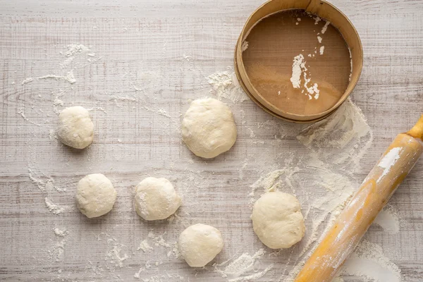 Balls of dough, sieve flour plunger on the table