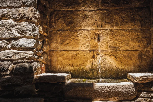 Small fountain in the stone wall
