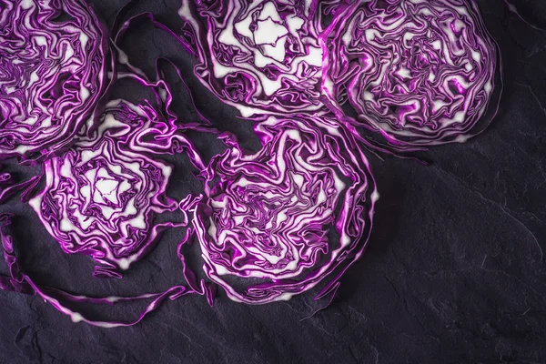 Sliced red cabbage on the black stone background top view