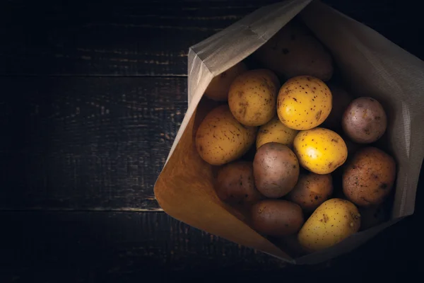 Potatoes in the paper bag on the wooden table top view