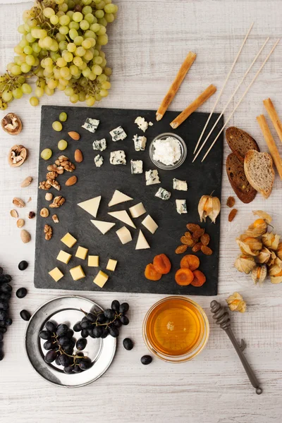 Cheese platter with different fruits and nuts top view