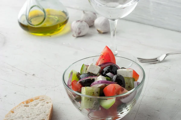 Greek salad with olive oil and bread on the white scratched table