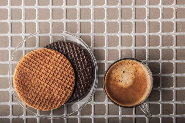 Wafers with cup of coffee on the relief background top view