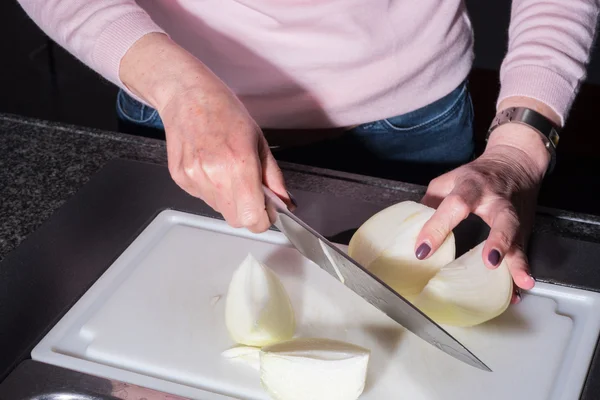 Woman is cutting big onions in the kitchen
