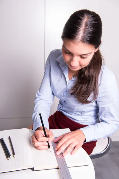 Young female engineer is drawing into open notebook
