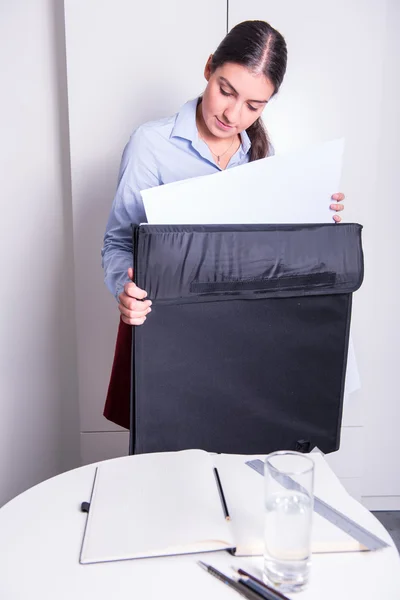 Female engineer is taking drawings out of a big folder