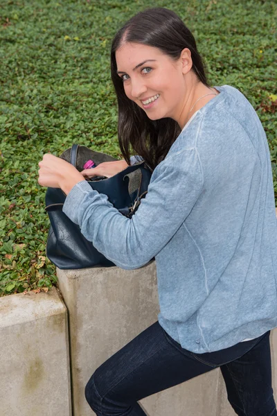 Beautiful young woman is searching something in her bag