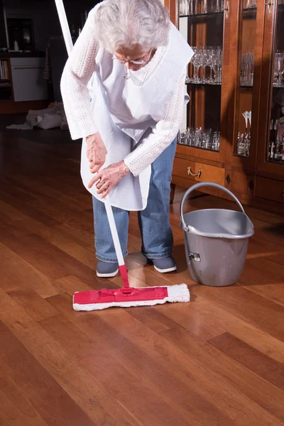 Active female senior is cleaning the floor