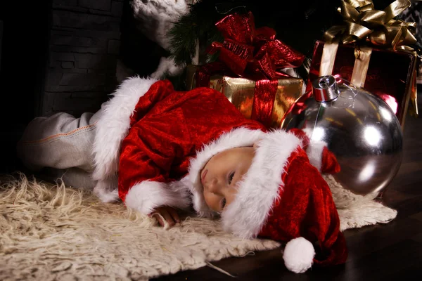 Baby Santa Claus sleeping under the Christmas tree