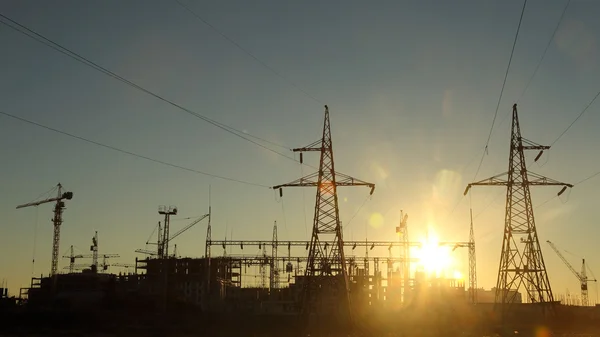Silhouettes of construction and power lines at sunset