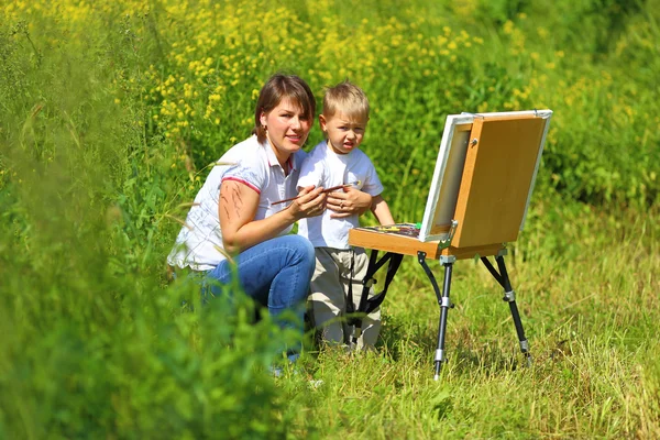 Mom and baby paint on an easel in the field