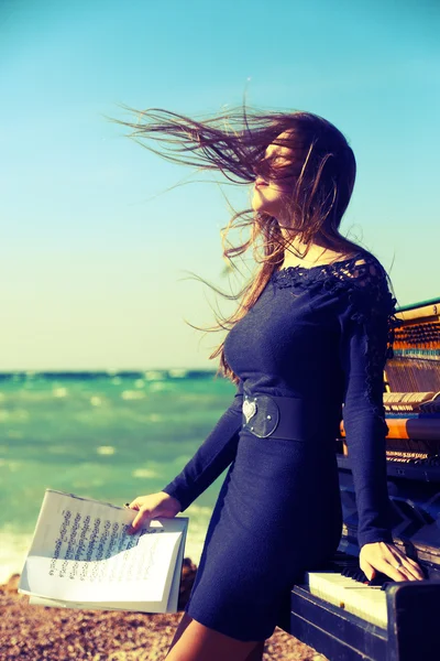 Beautiful girl with notes from an old piano on the beach