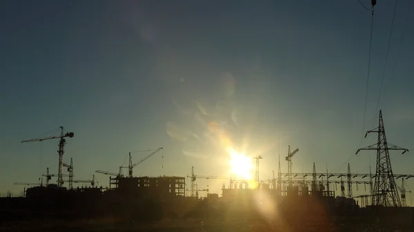 Silhouettes of construction and power lines at sunset