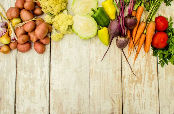 Food frame, market fresh food. Assorted organic vegetables and spices for healthy cooking and lifestyle on rustic wooden background with wooden cutting board in middle and copy space for text