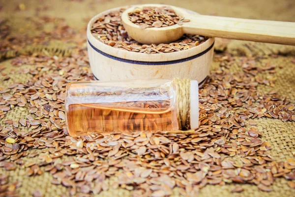 Heap of brown linseed, flax seeds spilling out of glass jar on wooden background, concept for healthy nutrition