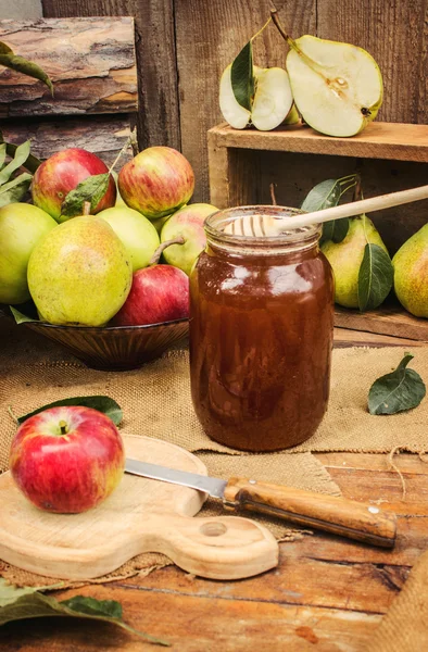 Juicy, ripe apples and pear with honey on wooden background.