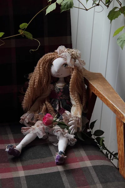 The doll with long hair sits in an armchair