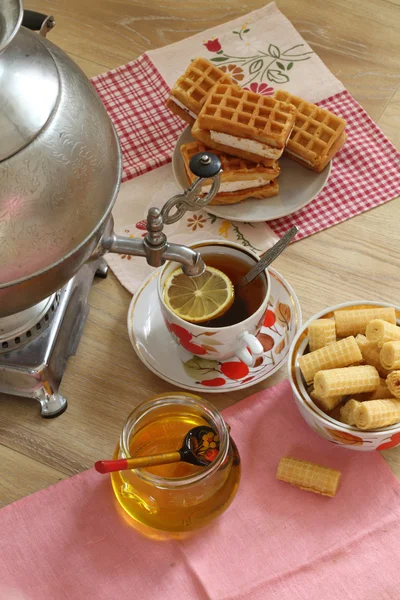 Tea from a samovar, with a lemon, honey, cakes and wafers