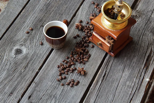 Cup of coffee and manual coffee grinder on a wooden background