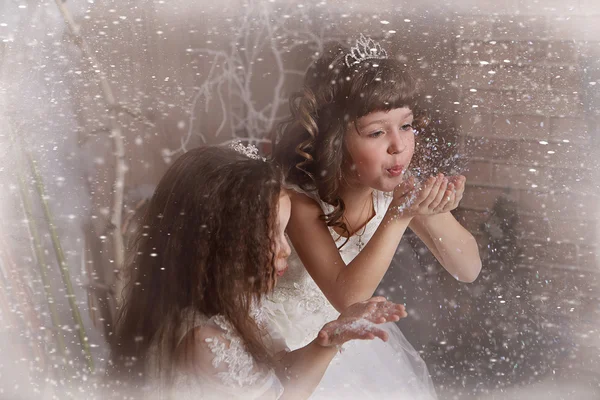 Beautiful little girls blow off snow from palms