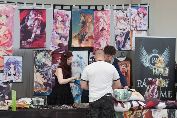 Visitor of animefest buys at market with anime wall scroll