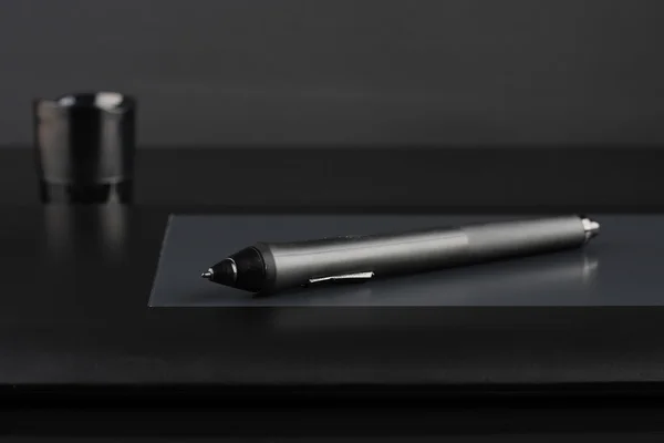 A close-up of  pen on graphic tablet on black  background