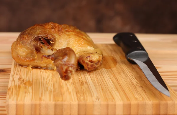 Roast duck on bamboo cutting board with knife