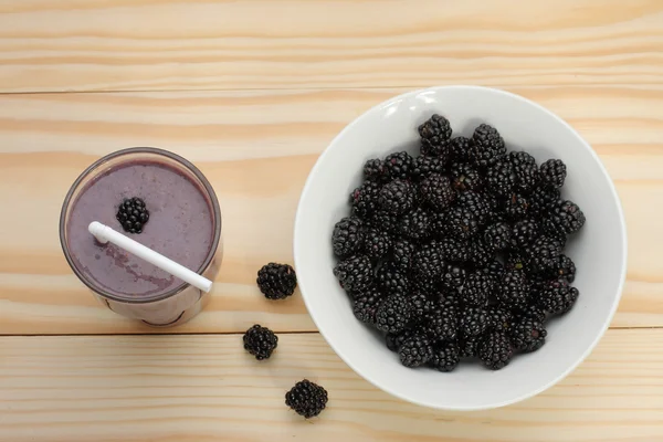 Smoothie from blackberries  in a glass and blackberries  on wood