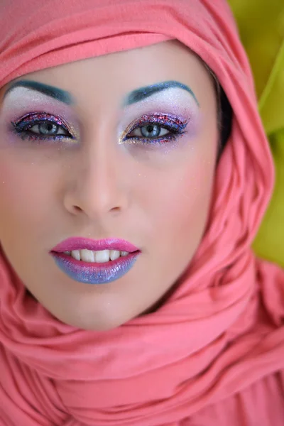 Beautiful girl in head wrap with bright creative colorful fashion makeup. Art beauty design. Blue eyebrows, glitter eyeshadows and two color gradient lips