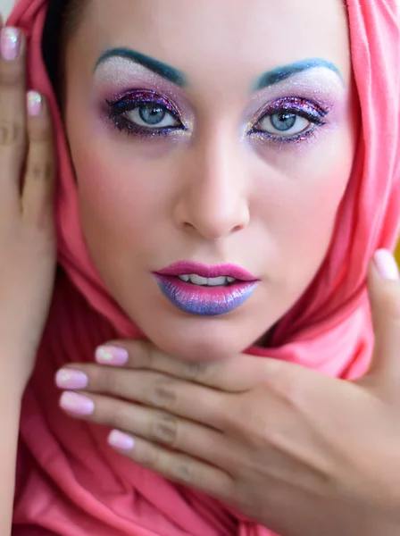 Beautiful girl in head wrap with bright creative colorful fashion makeup. Art beauty design. Blue eyebrows, glitter eyeshadows and two color gradient lips