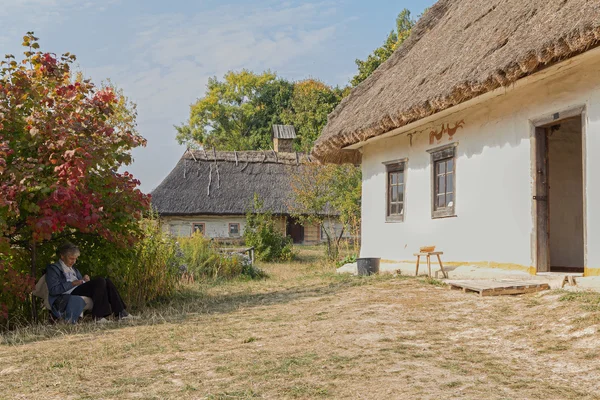 Kiev, Ukraine - October 06, 2015:  Elderly woman - caretaker in museum of Architecture and Life Pirogovo resting in the shade