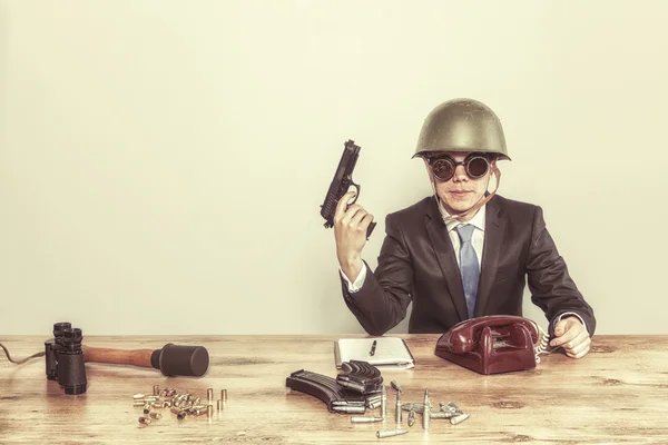 Vintage military businessman sitting at office desk with hand gun